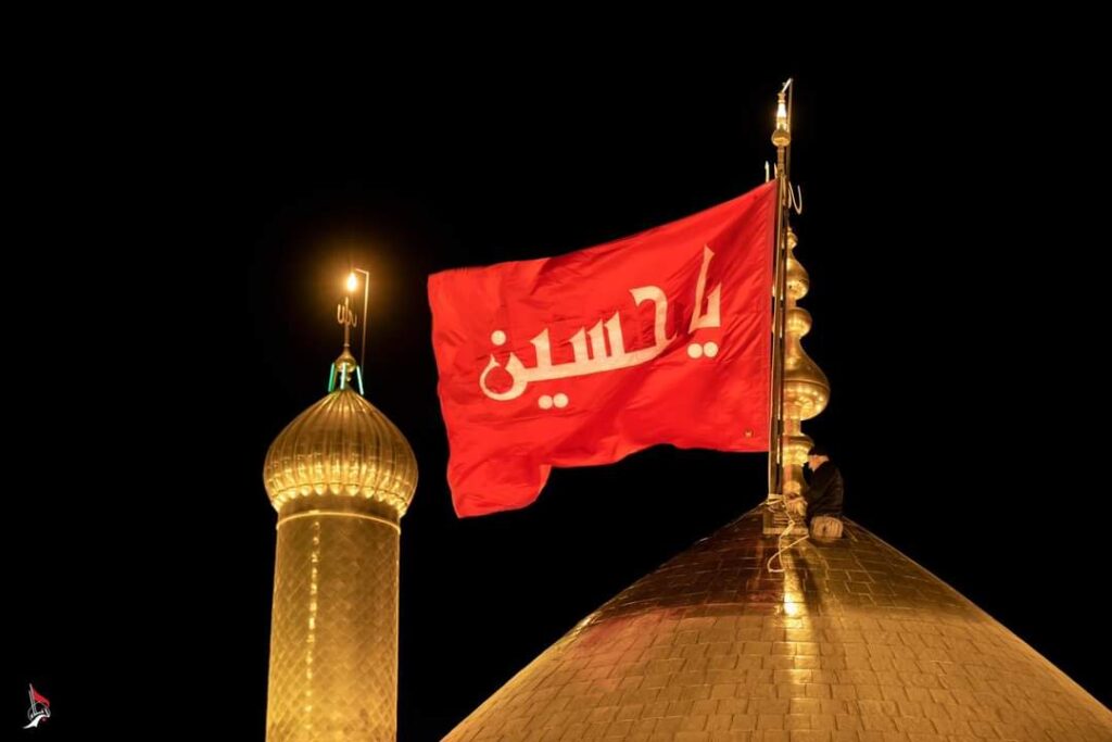 Black flag with "Ya Hussain" written on it atop the golden dome of Karbala shrine