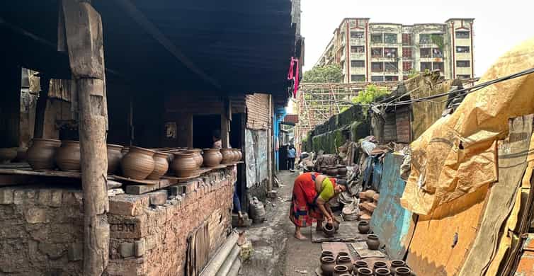 A woman working in a narrow Dharavi lane surrounded by clay pots, traditional kilns, and old buildings.
