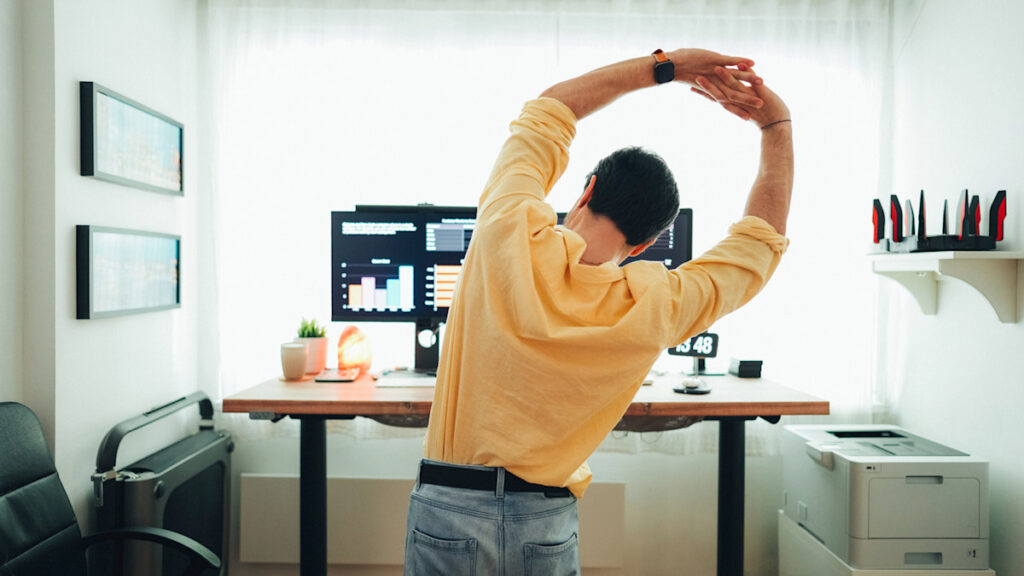 Person stretching beside their desk during a work break, promoting movement and mental refreshment while working from home.