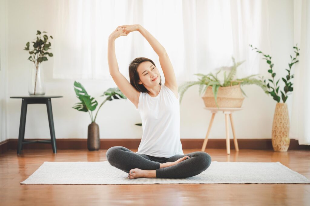 Woman practicing yoga in a peaceful home environment, promoting physical movement and mental well-being while working from home.